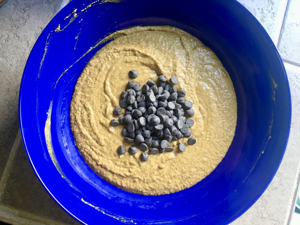 blue bowl with pumpkin oatmeal muffin batter and chocolate chips on top