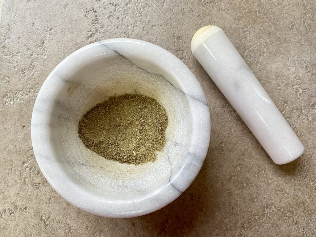 dried herbs that have been ground into a powder in a pestle and mortar