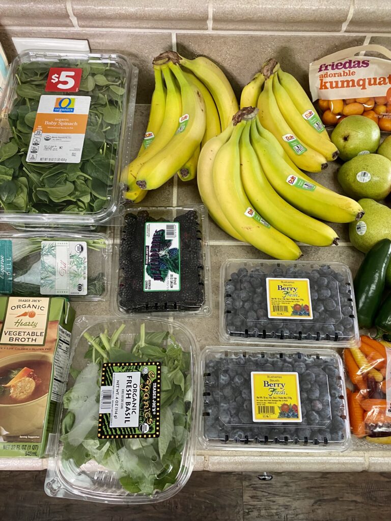 counter filled with fresh bananas and berries from budget grocery haul