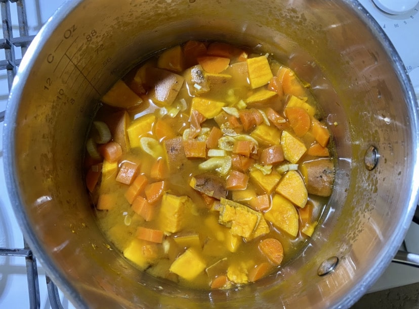pot of sweet potatoes, carrots and garlic to make chili queso mac